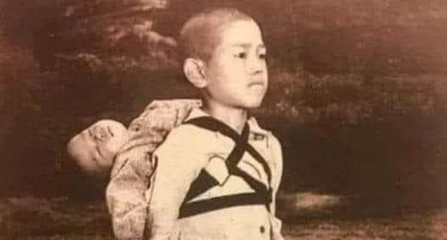 Японско момче стои мирно след като е довело мъртвия си